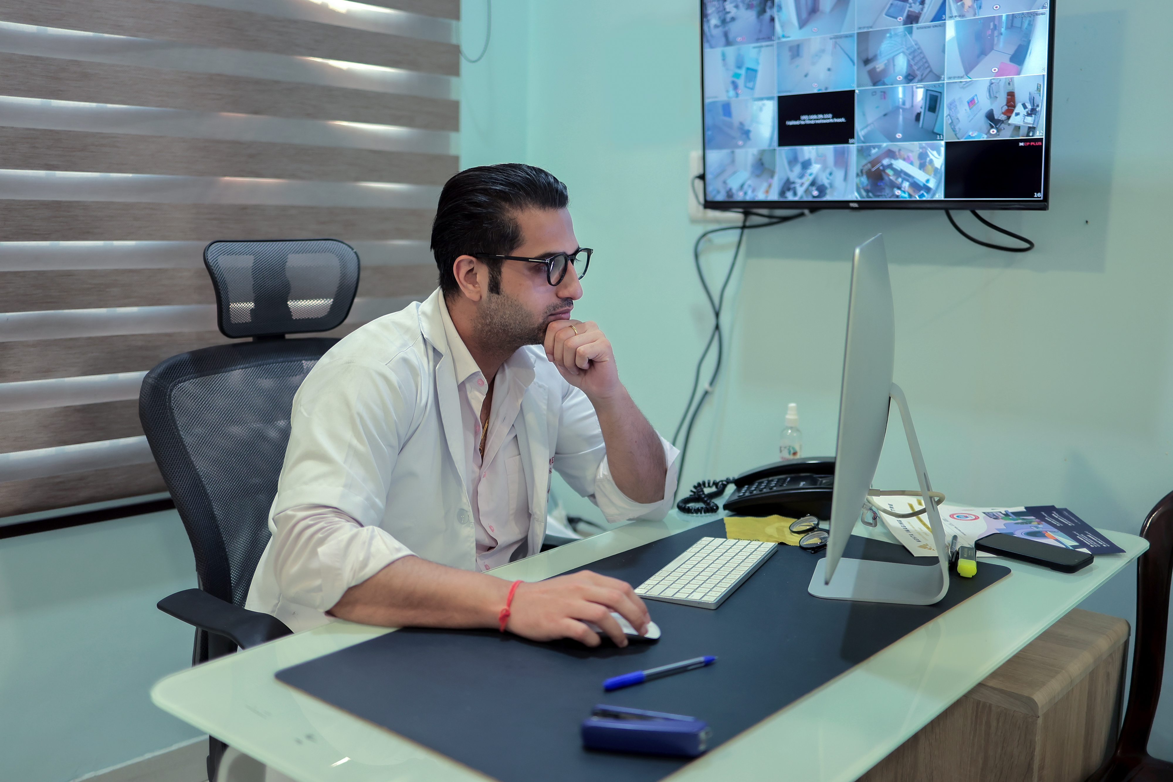 Technician operating the controls of a GE MRI machine with a patient inside.