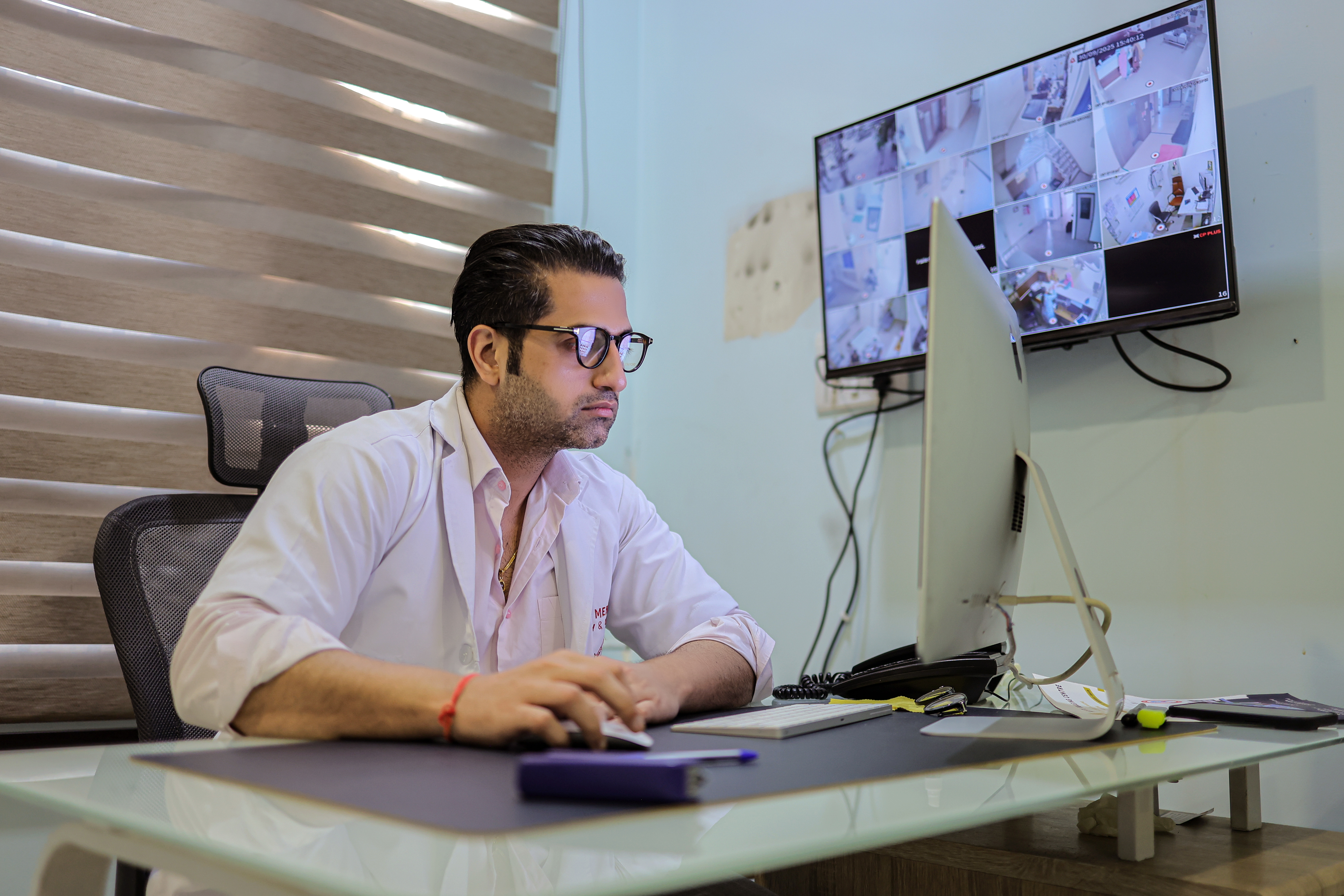 Technician operating the controls of a GE MRI machine with a patient inside.